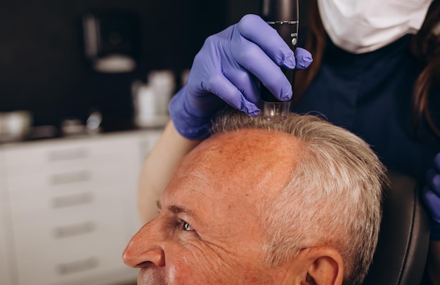 Foto un anciano está siendo examinado en una clínica de trasplante de cabello.