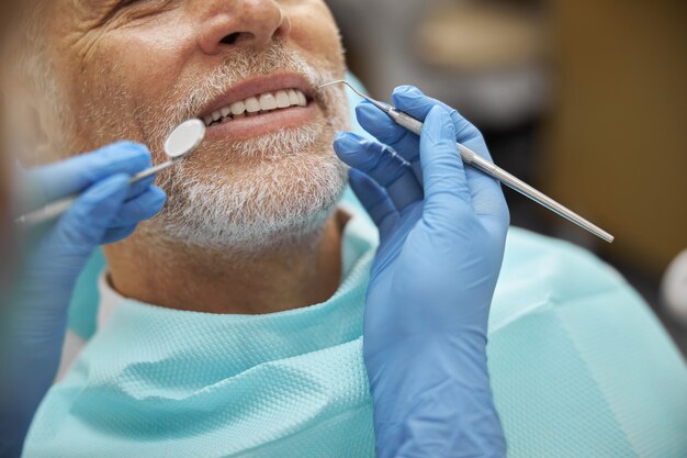 Foto un anciano sonriendo mientras un dentista le examina los dientes