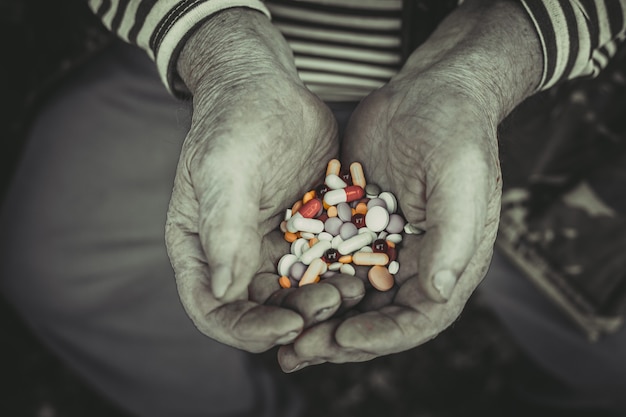 Foto anciano sosteniendo pastillas en las manos