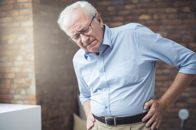 Un anciano se sostiene el estómago con dolor.