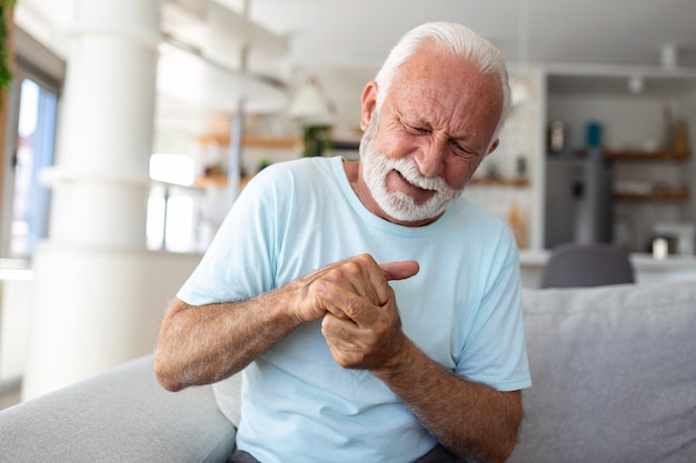 Anciano tiene dolor en los dedos y las manos Anciano con dolor en los dedos Hombre masajeando su mano y muñeca artríticas