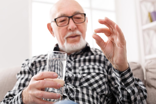 Anciano tomando pastillas con vaso de agua. Cuidado de la salud, tratamiento, concepto de envejecimiento.
