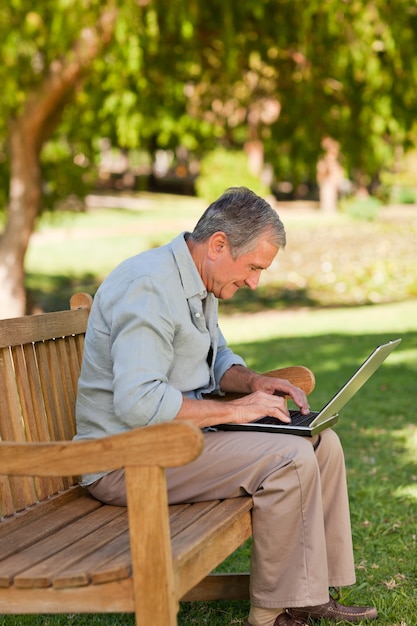 Anciano trabajando en su computadora portátil en el parque