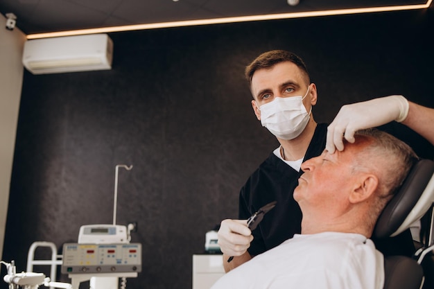 Anciano visitando a un médico masculino para cirugía plástica