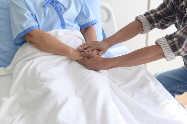 Un anciano visitando a una paciente de cáncer con pañuelo en la cabeza en el hospital