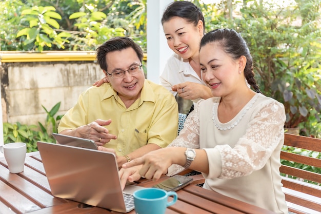 Ancianos amigos asiáticos que usan computadoras portátiles y tabletas en hogares de ancianos.