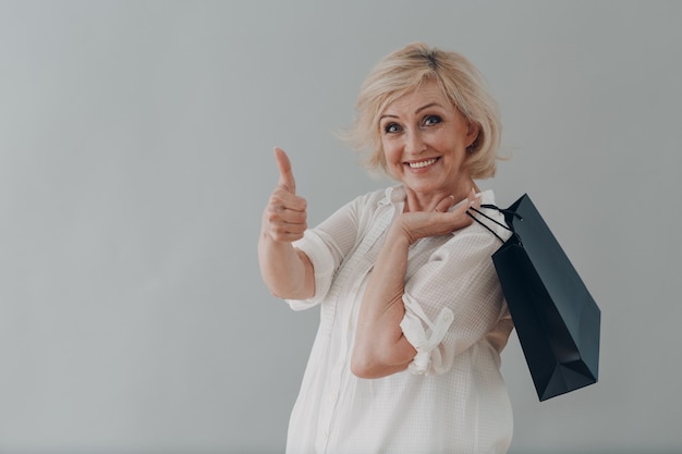 Ancianos anciana caucásica retrato retrato de cabello gris con bolsas de la compra sobre fondo gris