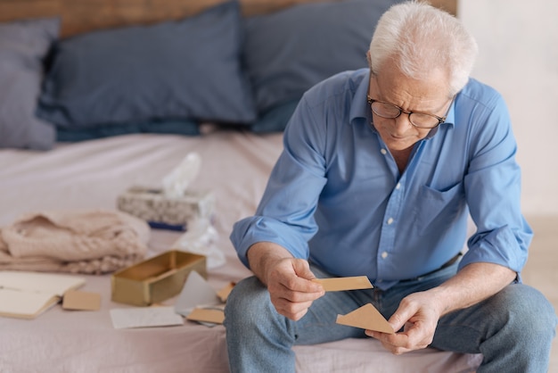 Ancianos deprimidos tristes sosteniendo un sobre y leyendo una nota vieja mientras piensan en su pasado