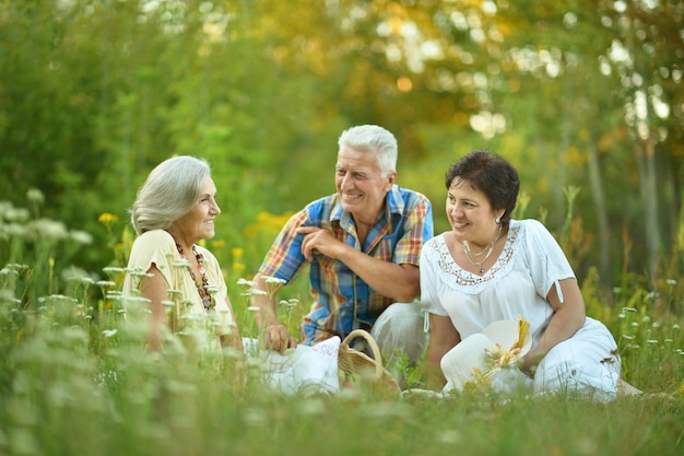 Ancianos felices descansando sobre la hierba en la naturaleza