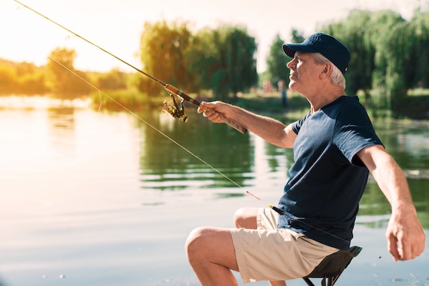 Ancião com gray hair fishing no rio no verão.