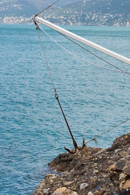 Ancla grande que cuelga en rocas cerca del mar