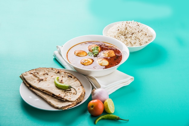 Anda curry o salsa masala de huevo, comida o receta picante india, servida con arroz Jeera, roti o naan, enfoque selectivo. Sobre una mesa colorida o de madera