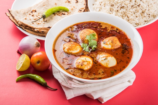Anda curry o salsa masala de huevo, comida o receta picante india, servida con arroz Jeera, roti o naan, enfoque selectivo. Sobre una mesa colorida o de madera