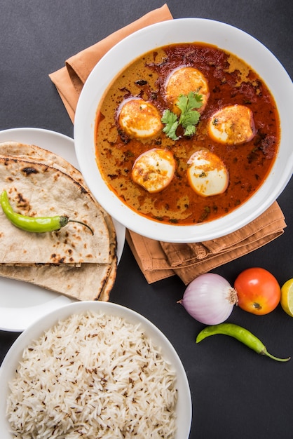 Anda curry o salsa masala de huevo, comida o receta picante india, servida con arroz Jeera, roti o naan, enfoque selectivo. Sobre una mesa colorida o de madera