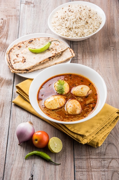 Anda curry o salsa masala de huevo, comida o receta picante india, servida con arroz Jeera, roti o naan, enfoque selectivo. Sobre una mesa colorida o de madera