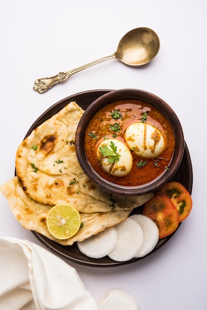 Anda curry o salsa masala de huevo, comida o receta picante india, servida con roti o naan, enfoque selectivo