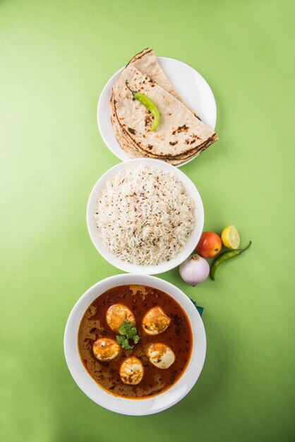 Anda Curry oder Egg Masala Soße, indisches scharfes Essen oder Rezept, serviert mit Jeera Reis, Roti oder Naan, selektiver Fokus. Über bunter oder hölzerner Tischplatte