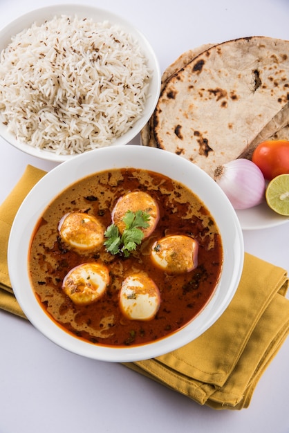Anda Curry ou molho de masala de ovo, comida ou receita picante indiana, servido com arroz Jeera, roti ou naan, foco seletivo. Sobre tampo de mesa colorido ou de madeira