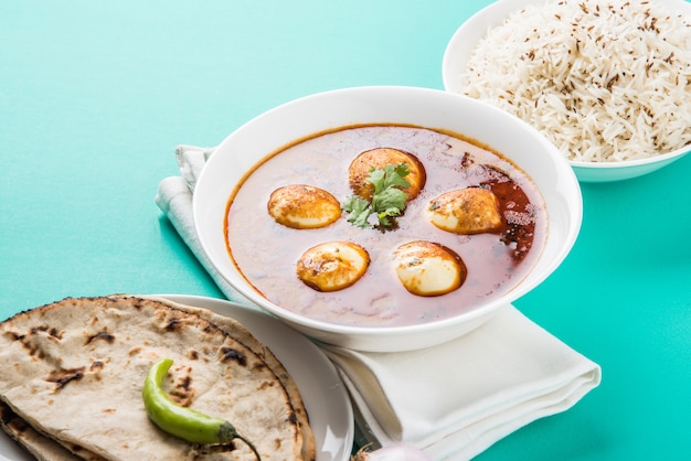 Anda Curry ou molho de masala de ovo, comida ou receita picante indiana, servido com arroz Jeera, roti ou naan, foco seletivo. Sobre tampo de mesa colorido ou de madeira