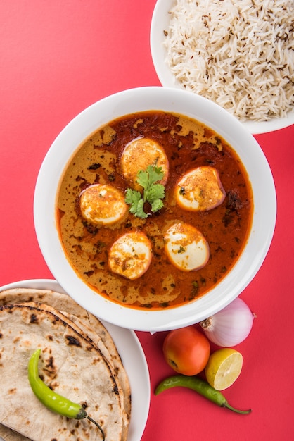 Anda Curry ou molho de masala de ovo, comida ou receita picante indiana, servido com arroz Jeera, roti ou naan, foco seletivo. Sobre tampo de mesa colorido ou de madeira