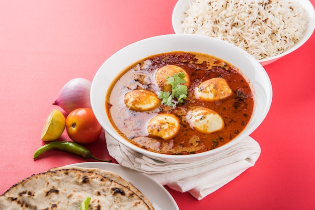 Anda Curry ou molho de masala de ovo, comida ou receita picante indiana, servido com arroz Jeera, roti ou naan, foco seletivo. Sobre tampo de mesa colorido ou de madeira