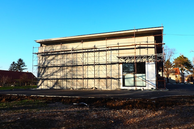 Andaime em uma nova casa de um andar Trabalhos de fachada Edifício comercial Edifício baixo de construção privada Reboco da parede de um edifício Construção de lojas Estruturas de produção de metal