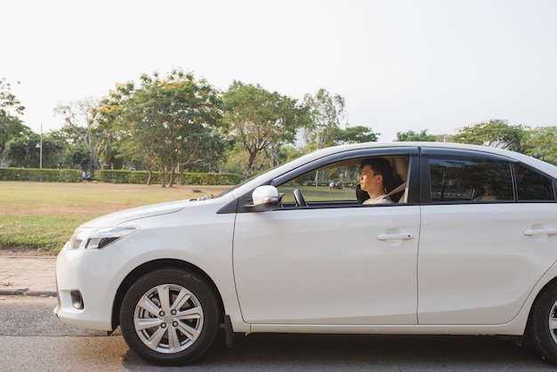 Andando em seu novo carro. Vista lateral de um jovem bonito dirigindo seu carro e sorrindo