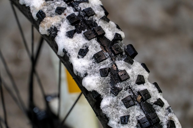 Andar en bicicleta en el invierno Neumático de bicicleta cubierto de nieve Bicicleta en el taller para reparar Rueda delantera y primer plano de nieve Grandes picos en un neumático grueso