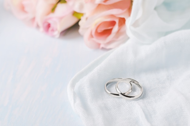 Anéis de casamento com rosas na mesa de madeira azul