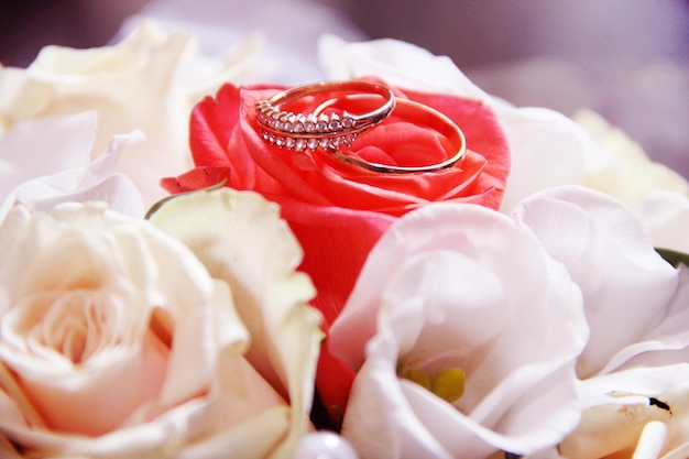 Anéis de casamento de ouro com buquê de flores de noiva