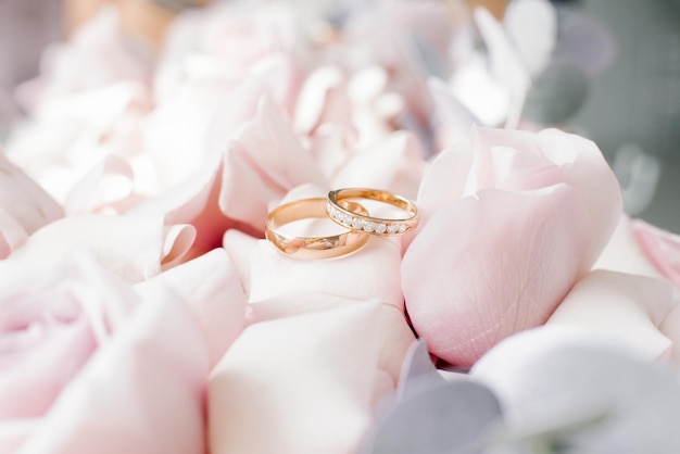 Anéis de casamento de ouro estão em delicadas rosas rosas fechadas