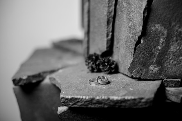 anéis de casamento em uma pedra ao lado dos anéis são cones amor conceito preto e branco foto