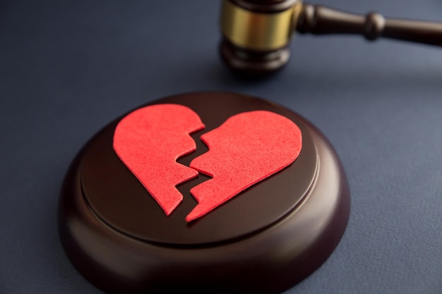 Anéis de casamento na figura de um coração partido de um martelo de árvore de um juiz em um fundo de madeira processos de divórcio