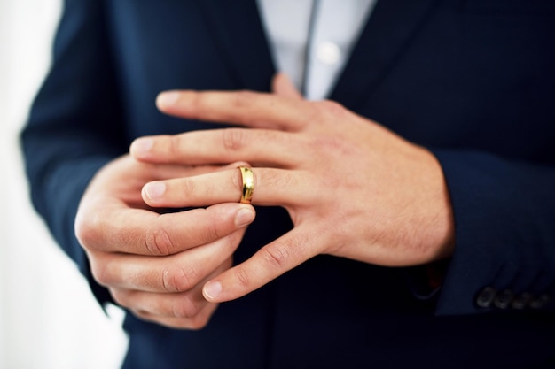 Anéis de casamento são símbolos de promessa de compromisso e lealdade Foto recortada de um noivo irreconhecível ajustando seu anel no dia do casamento