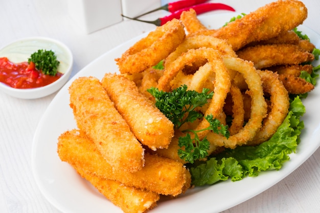 Anéis de lula frita com palitos de queijo em um prato branco