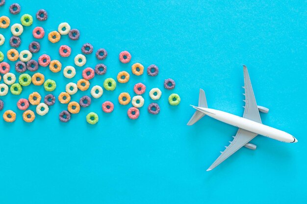 Anéis de milho de frutas coloridos e avião de brinquedo em um fundo azul