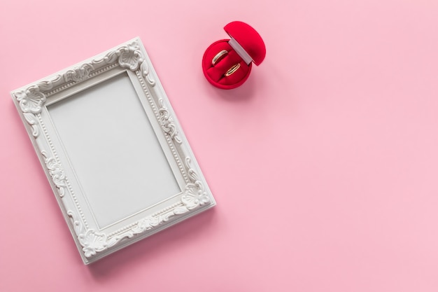 Foto anéis de ouro em caixa vermelha e moldura com espaço vazio em rosa