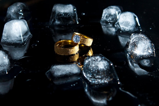 Foto anéis em um fundo escuro. alianças de casamento. joalheria. gelo