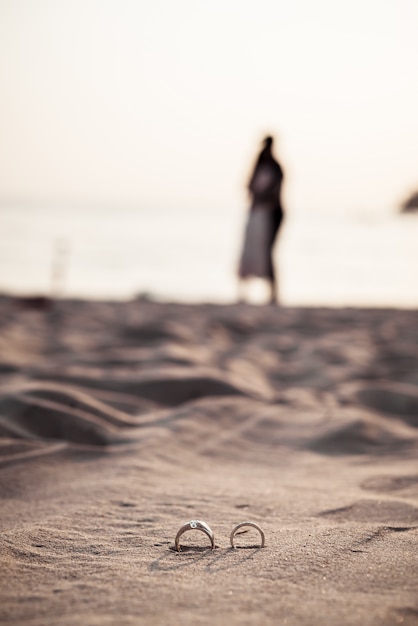 anéis na praia com a noiva e o noivo em fundo