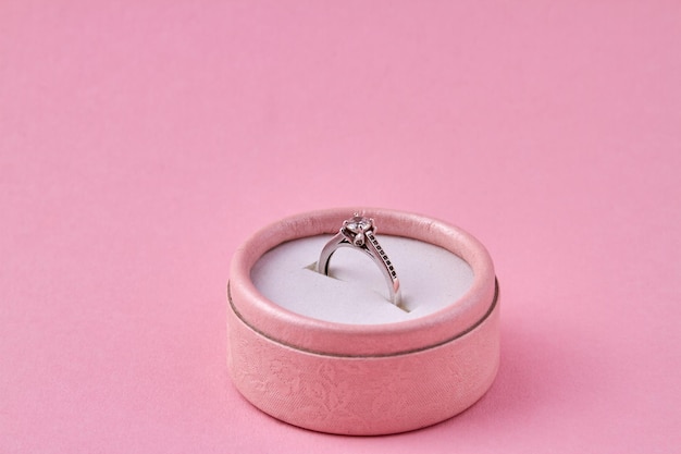 Anel com pedra preciosa em caixa de presente redonda em fundo rosa