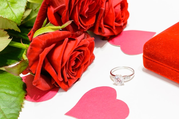 anel de casamento com diamante, corações de papel rosa e rosas vermelhas isoladas no fundo branco, macro