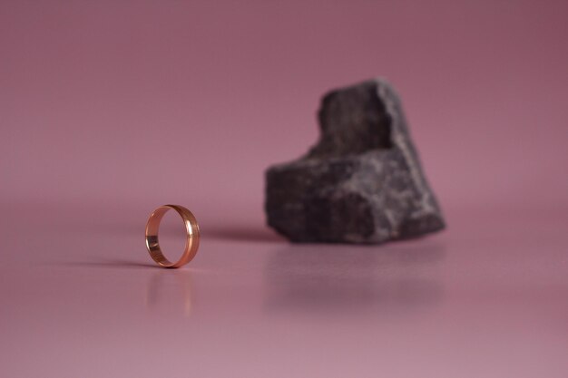 Anel de casamento com uma pedra em forma de coração em um fundo rosa