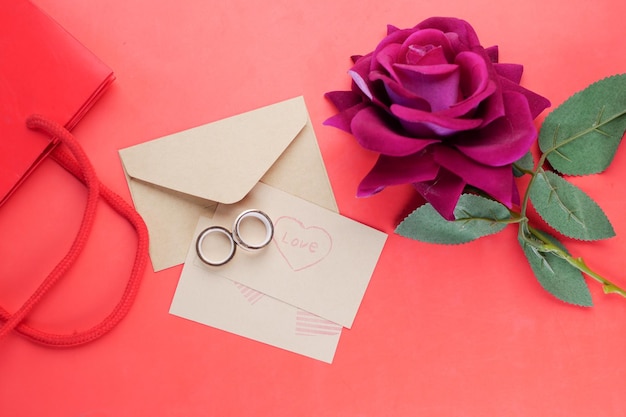 Anel de casamento e caixa de presente e flor rosa em vermelho