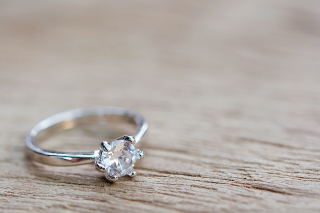 Foto anel de diamante, aliança de casamento na prancha de madeira com espaço de cópia