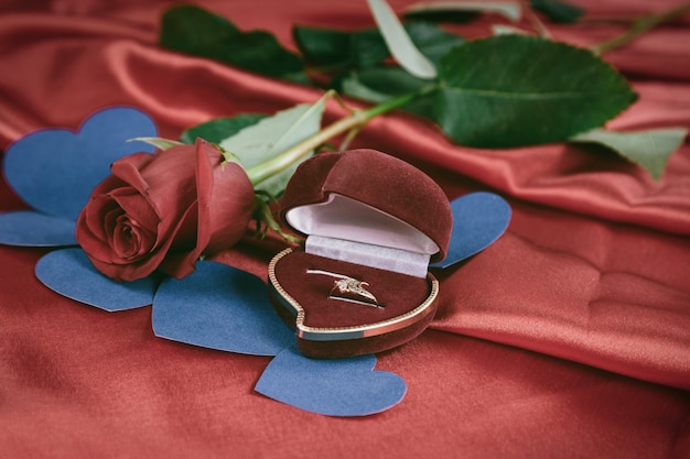 Anel de diamante e rosa em fundo vermelho brilhante