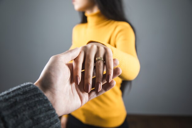 Anel de mulher com mão de homem em fundo cinza