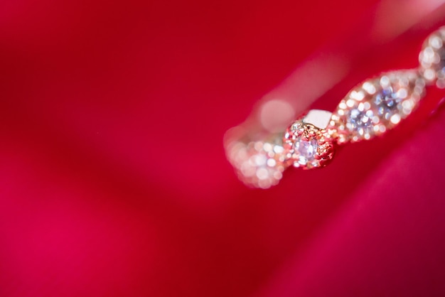 Anel de ouro rosa de luxo de joias com pedra preciosa de safira em fundo de textura de tecido vermelho