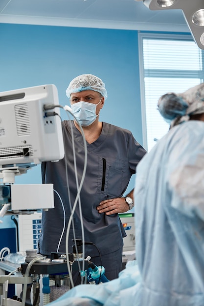 Foto anestesiólogo haciendo un seguimiento de las funciones vitales del cuerpo durante la cirugía cardíaca