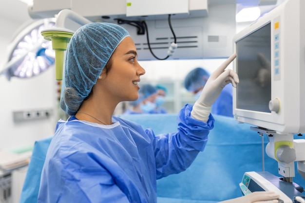 Foto anestesiólogo que realiza un seguimiento de las funciones vitales del cuerpo durante la cirugía cardíaca cirujano que mira el monitor médico durante la cirugía médico que controla el estado de salud del paciente