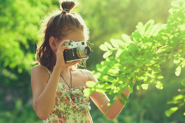Anfänger Fotograf. Ein kleines Mädchen fotografiert einen Baum auf ihrer Filmfotokamera